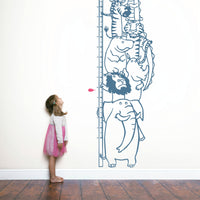 Height chart wall sticker with a pile of animals with a young girl nearby.