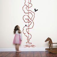 Height chart wall sticker of a monkey with a jetpack with a young girl nearby next to a rocking horse.