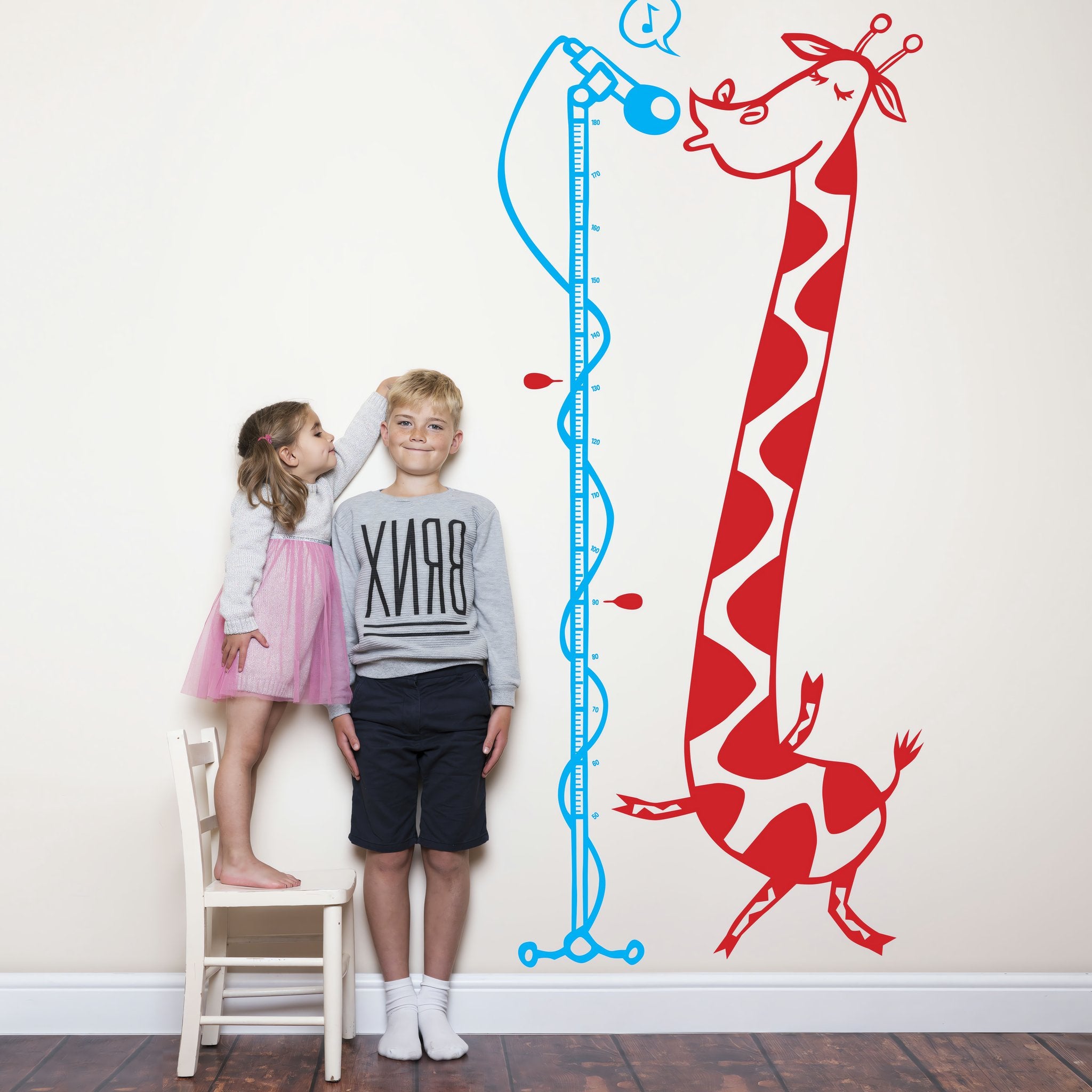 Height chart wall sticker of a giraffe singing into a microphone with a young boy and girl nearby.