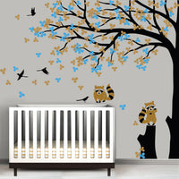 Tree wall sticker with leaves blowing and birds in a nursery with a crib.