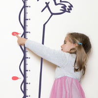 Height chart wall sticker of a cartoon crocodile with a young girl pointing at their charted height.