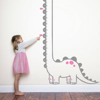 Height chart wall sticker of a long necked dianosaur with a young girl nearby.