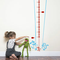 Height chart wall sticker of a kite being flown by a cat and dog with a young girl playing with kermit the frog nearby.
