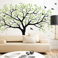 Large tree wall sticker with birds in a living room with a couch, coffee table and lamp.