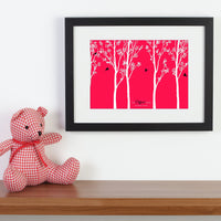 Personalized framed print with trees and family of birds with names next to pink cuddly toy.