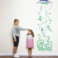 Height chart wall sticker with a boat and undersea monsters beneath the surface with a young boy and girl nearby.