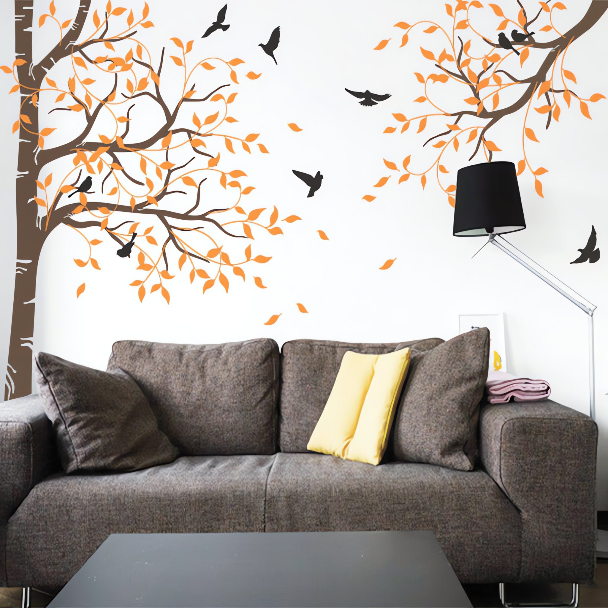 Tree wall sticker with birds and a hanging branch on the right in a living area with a sofa.