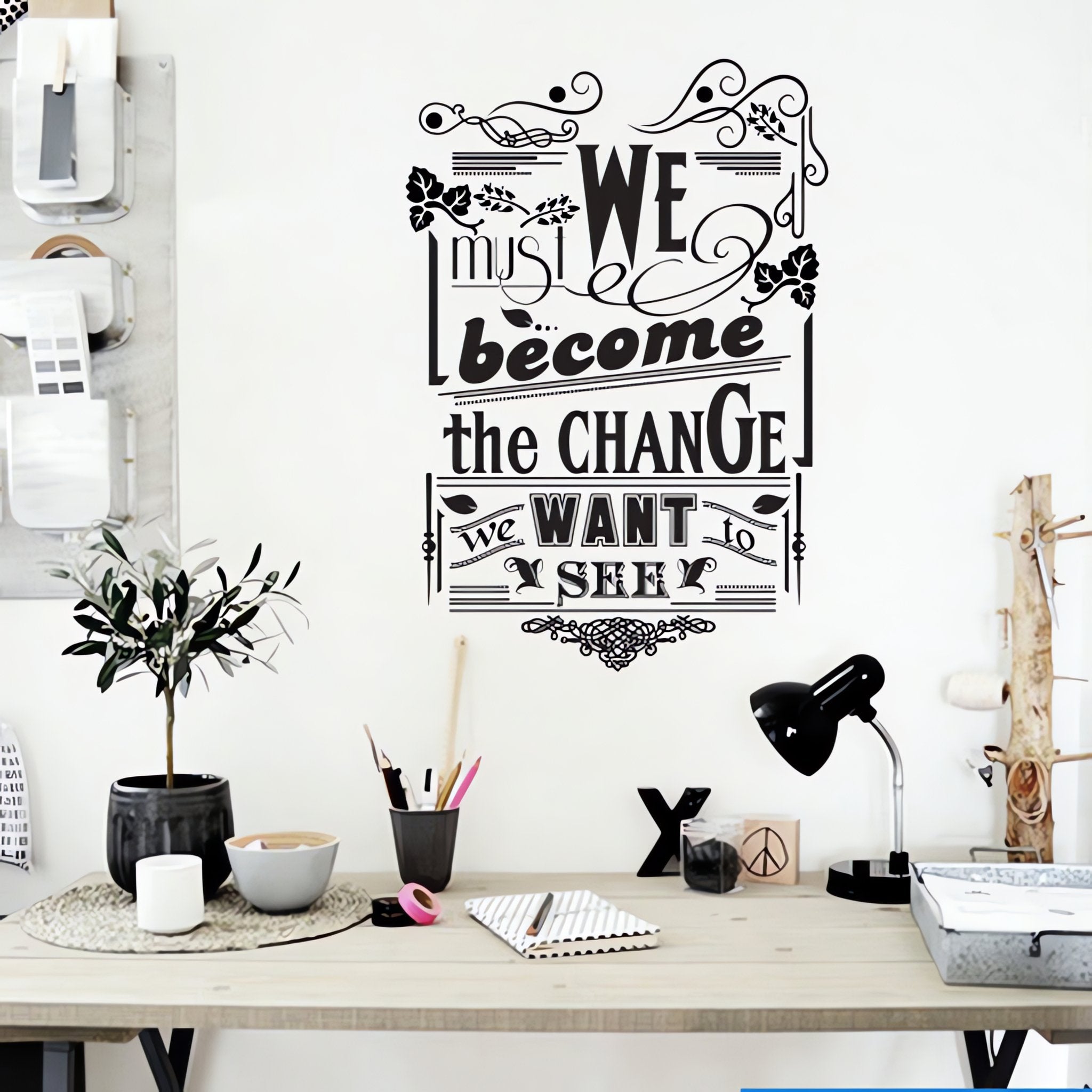 Wall quote sticker with text "We Must Become the Change We Want to See" in an office with a desk and office equipment.