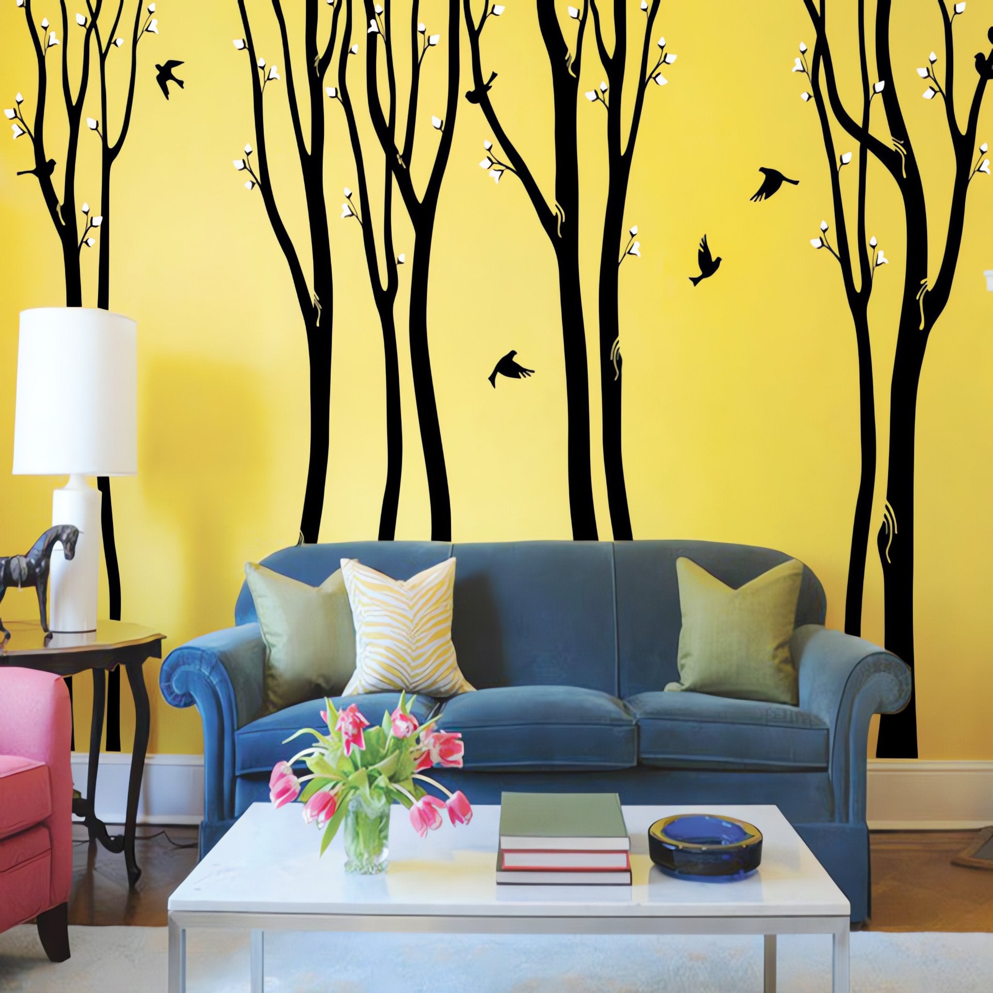 Tree wall sticker with several tall trees and birds in a living room with a sofa, a char and a coffee table.
