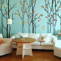 Tree wall sticker with many thin trees in a living room with a sofa and several chairs.