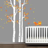 Tree wall sticker with orange leaves and a fox playing in a nursery with a crib.