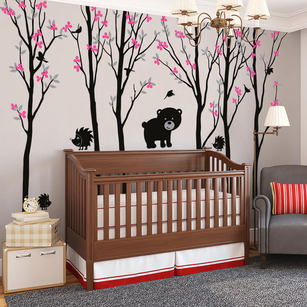 Tree wall sticker with several baby bears and hedgehogs in a nursery with a crib and an armchair.