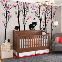 Tree wall sticker with several baby bears and hedgehogs in a nursery with a crib and an armchair.