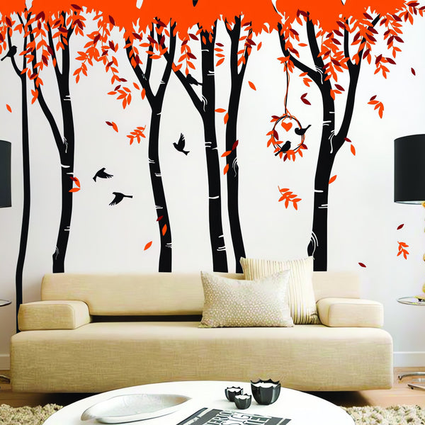 Tree wall sticker with falling leaves and birds in a living room with a couch, coffee table and lamps.