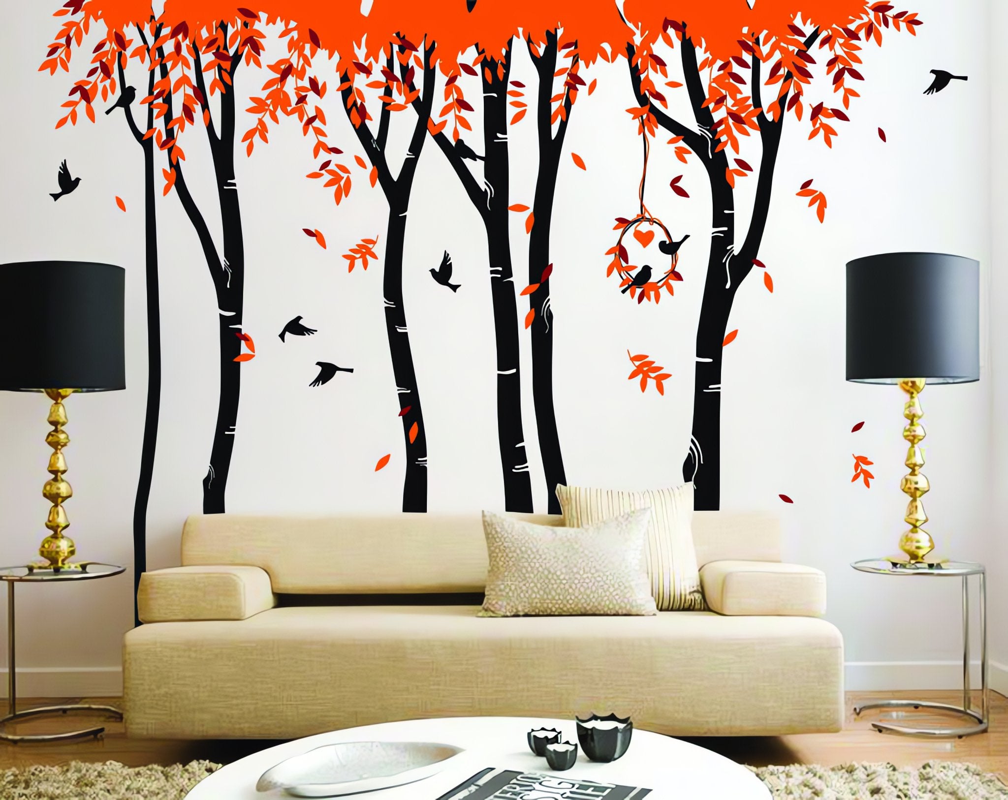 Tree wall sticker with falling leaves and birds in a living room with a couch, coffee table and lamps.