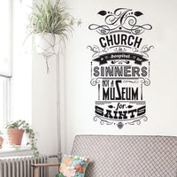 Wall quote sticker with text "A Church Is A Hospital For Sinners, Not A Museum For Saints" next to a hanging plant and a window in brightly lit room.