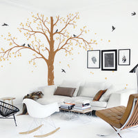 Tree wall sticker with birds in a living room with seating and framed pictures.