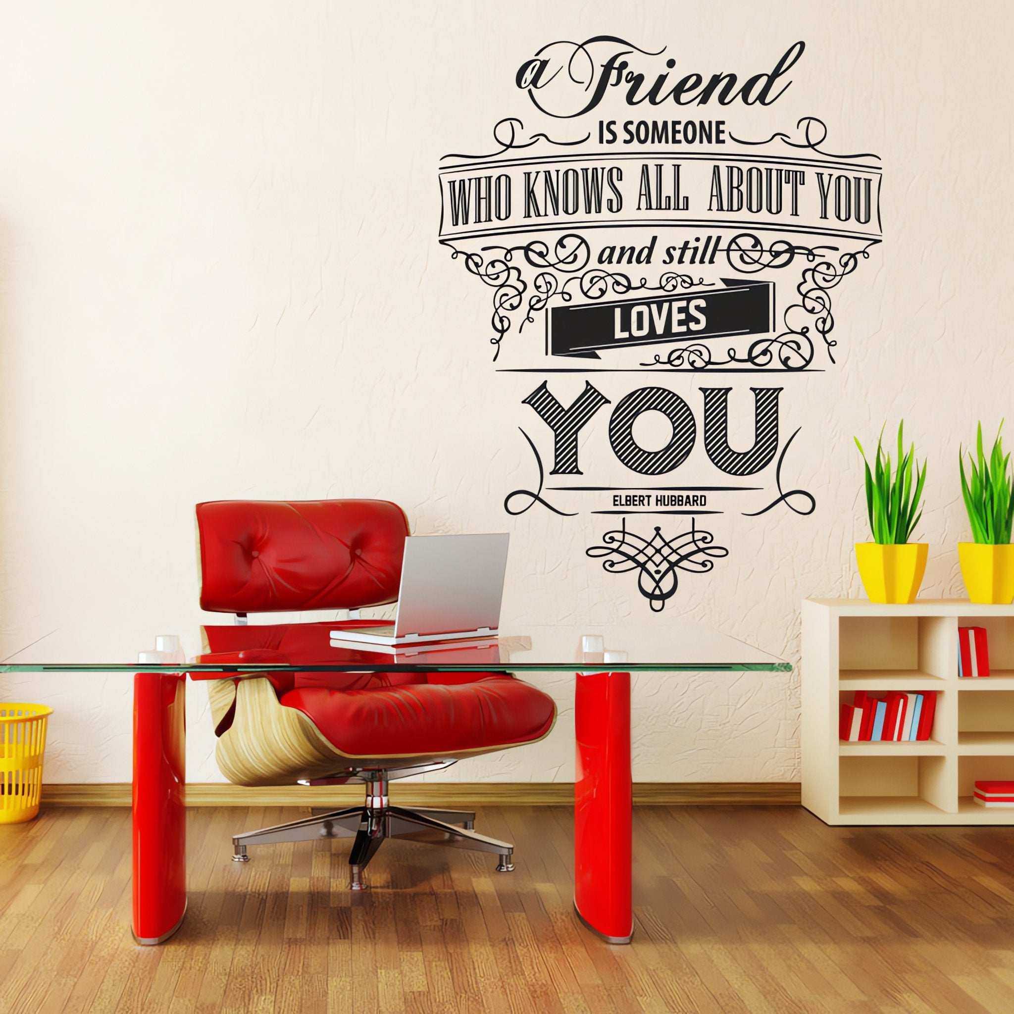 Wall quote sticker with text "A Friend Is Someone Who Knows All About You And Still Loves You" in an office with a desk, chair, office equipment and shelf.