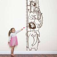 Height chart wall sticker with a pile of animals with a young girl nearby.