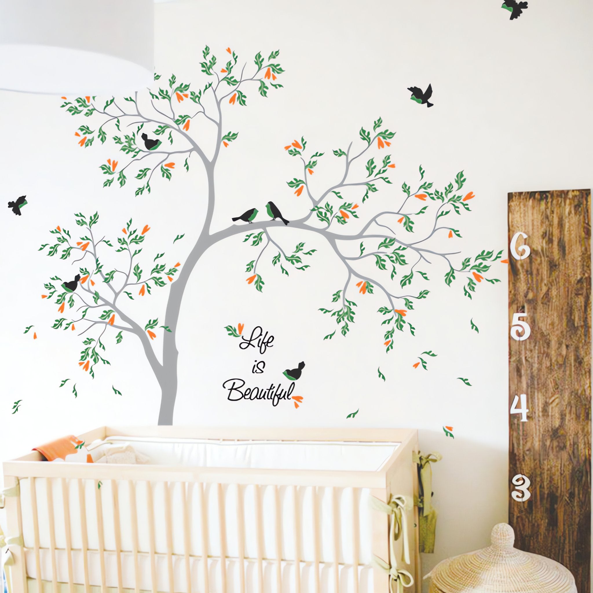 Tree wall sticker with birds and a child's name in a nursery with a crib.
