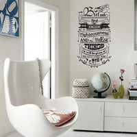 Wall quote sticker with text "But Seek First His Kingdom And His Righteousness And All These Things Will Be Given To You As Well" in a living room with modern chair and decor.