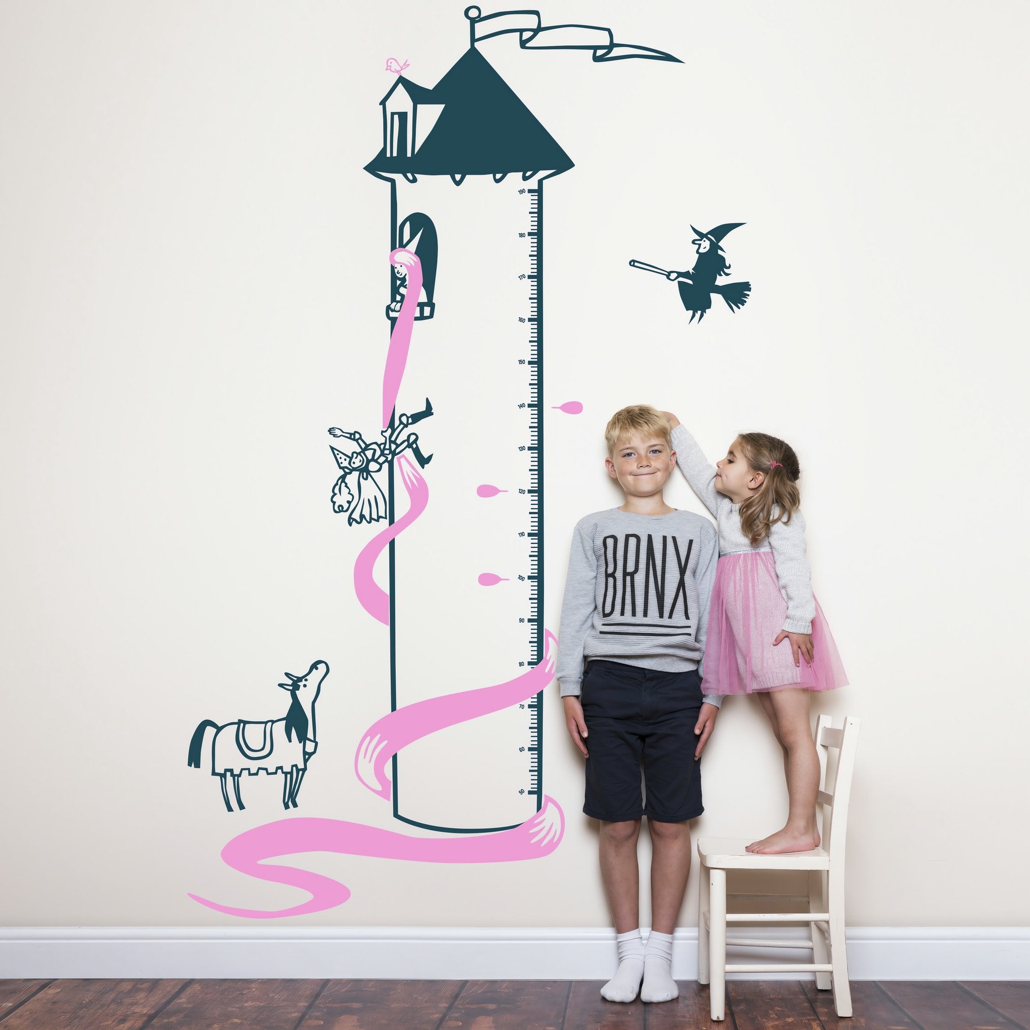 Height chart wall sticker of rupunzel in a tower being rescued py a prince with a young boy and girl nearby.