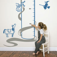 Height chart wall sticker of rupunzel in a tower being rescued py a prince with a young girl sitting on a chair.