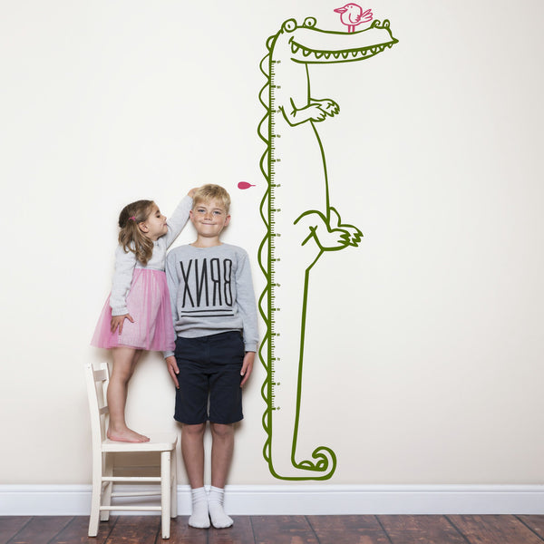 Height chart wall sticker of a cartoon crocodile with a young boy and girl nearby.
