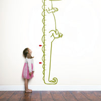 Height chart wall sticker of a cartoon crocodile with a young girl nearby.