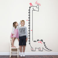 Height chart wall sticker of a long necked dianosaur with a young girl and boy nearby.