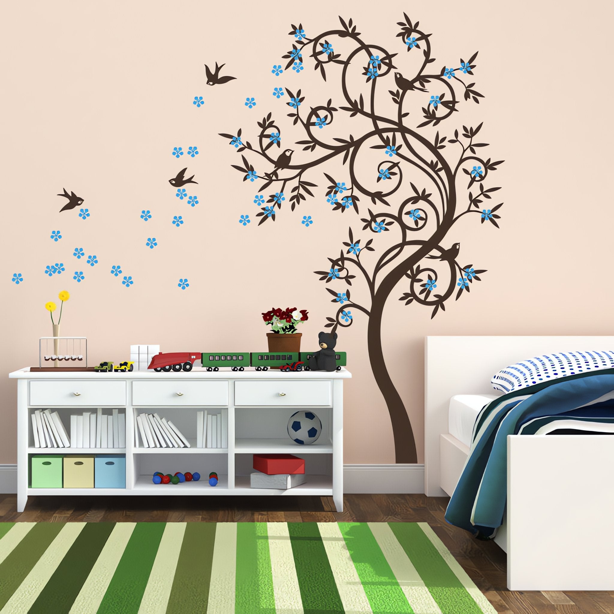 Tree wall sticker with leaves blowing and birds in a bedroom with a bed and a small shelving unit.
