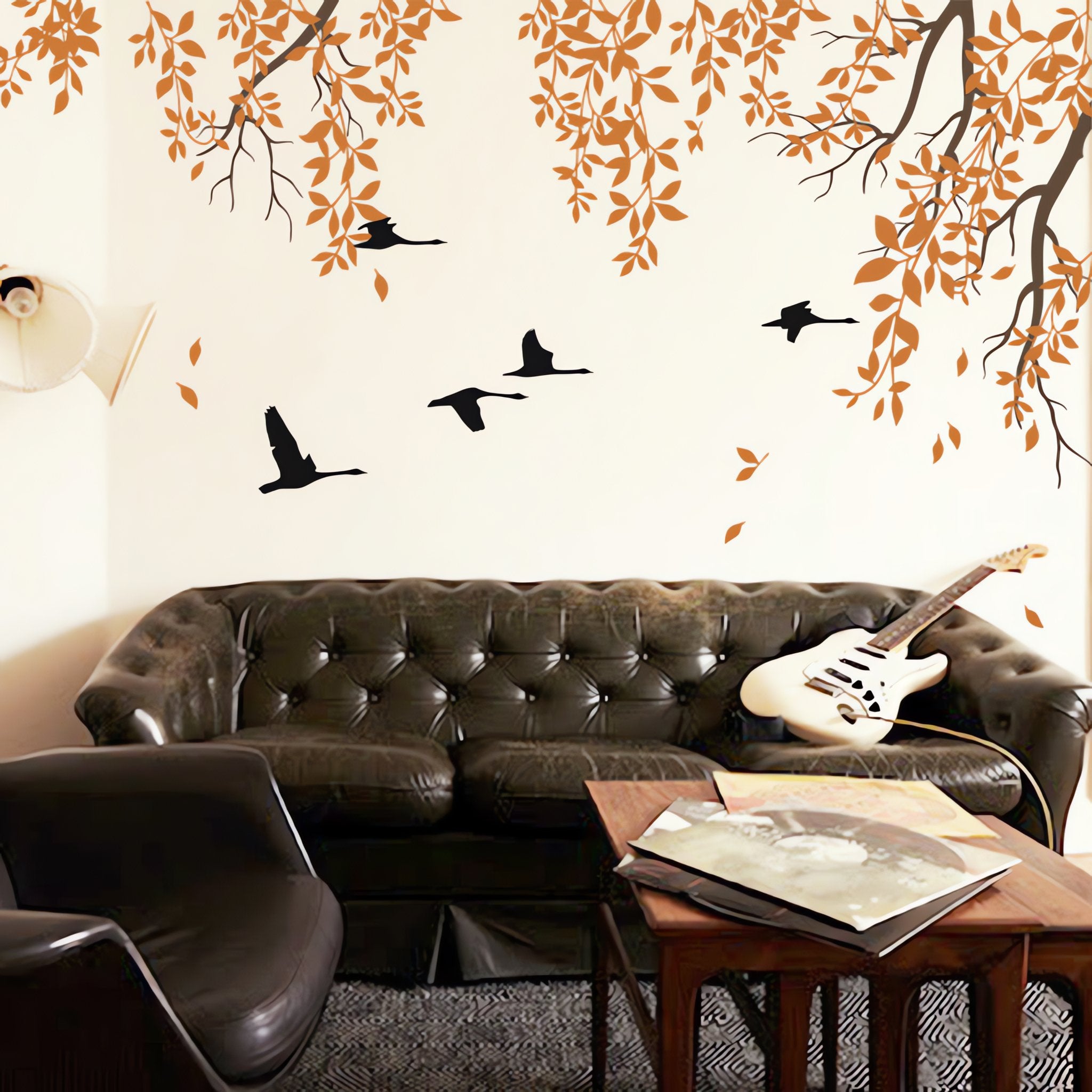 Stylish tree wall sticker with hanging branches and birds flying in a living room with a leather couch and coffee table.