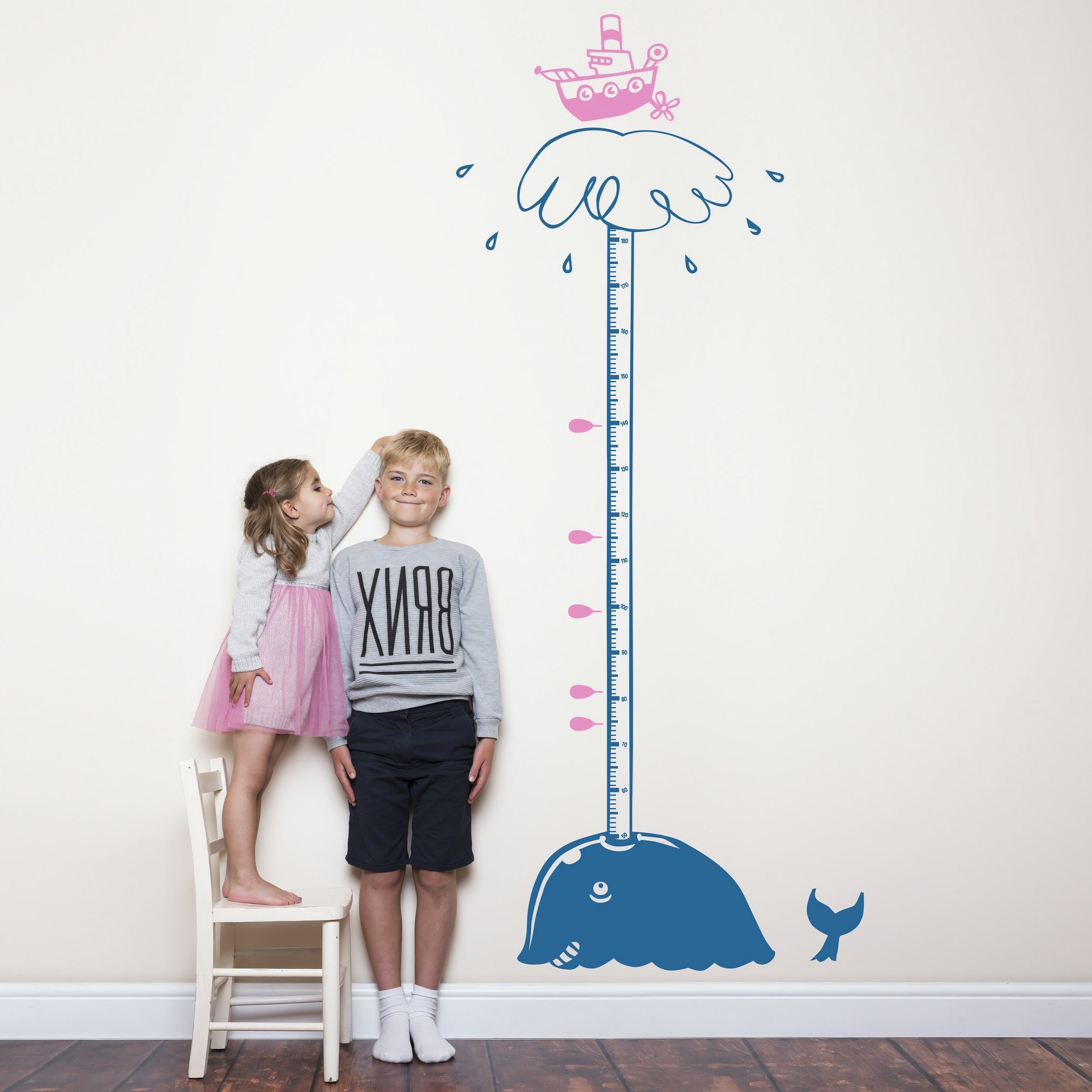 Height chart wall sticker of a whale blowing water from its blow-hole with a young boy and girl nearby.