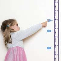Height chart wall sticker of a whale blowing water from its blow-hole with a young girl pointing at their charted height.