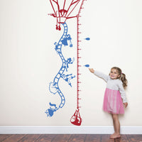 Height chart wall sticker of a hot air balloon taking off, a young girl nearby with a young girl pointing at their charted height.