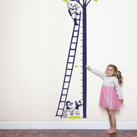 Height chart wall sticker of a kitten being rescued from a tree with a young girl nearby.