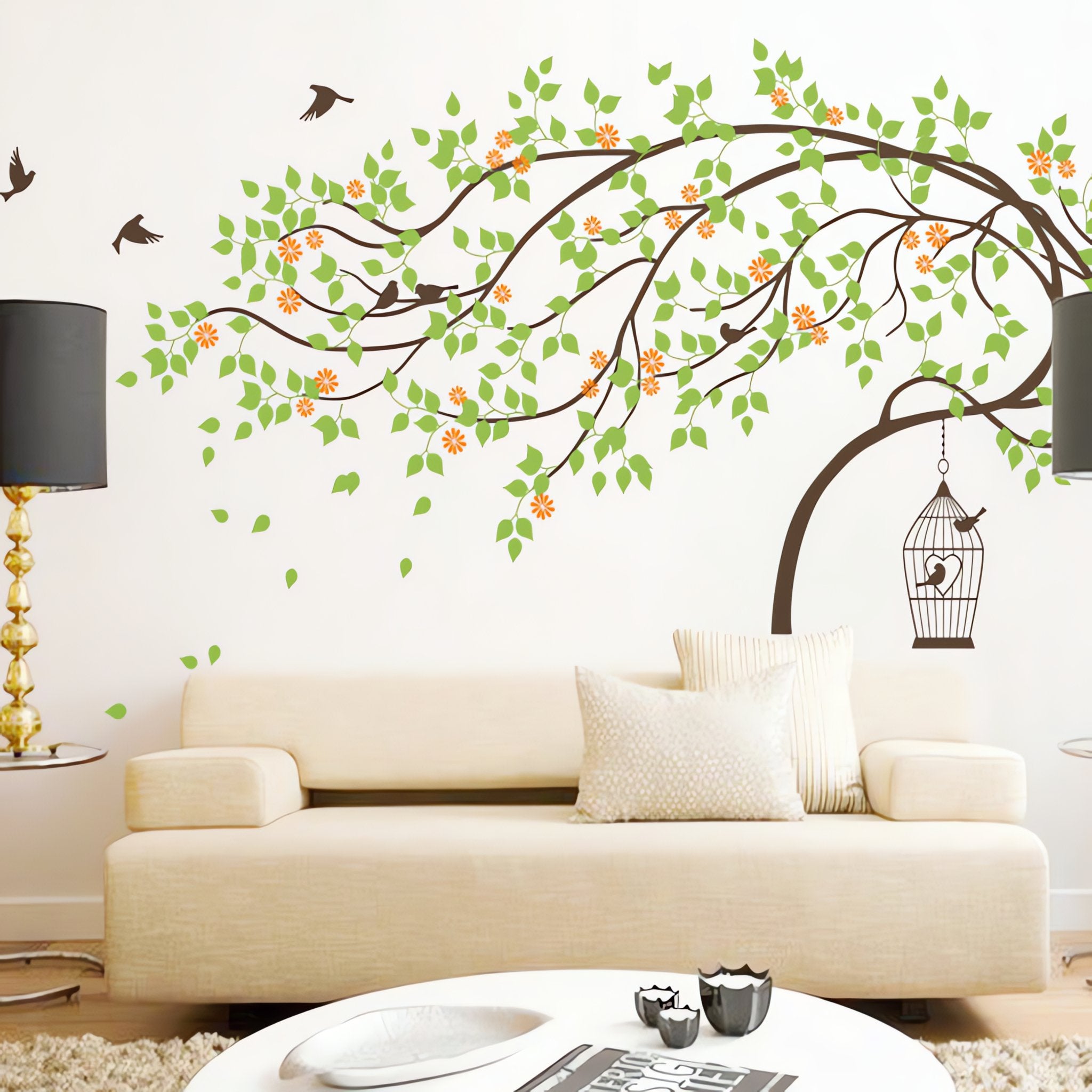 Large wall tree sticker with a leaning tree, birds and birdcage in a living room with a couch and coffee table.