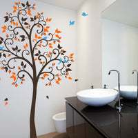 Tree wall sticker with curved branches and birds in a bathroom with a sink and mirror.