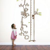 Height chart wall sticker with monkeys hanging from a tree to form a chain with a young girl nearby.