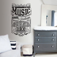 Wall quote sticker with text "Music Is What Feelings Sound Like" next to a dresser, a couch and a mirror.