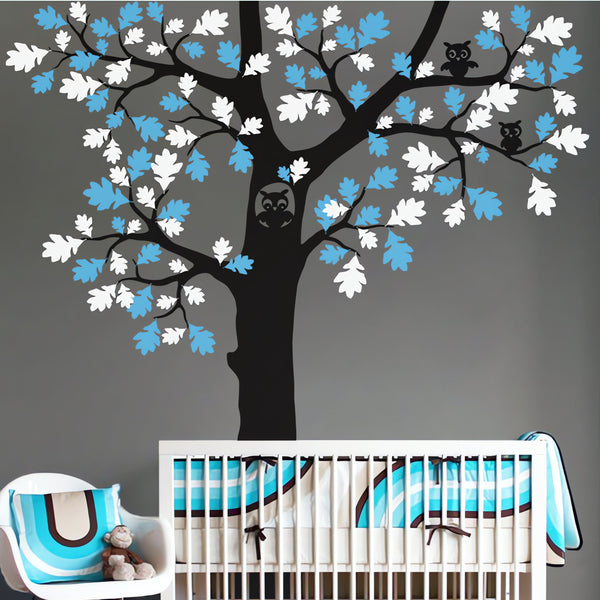 Tree wall sticker with oak leaves and an owl in a nursery with a crib and a chair.