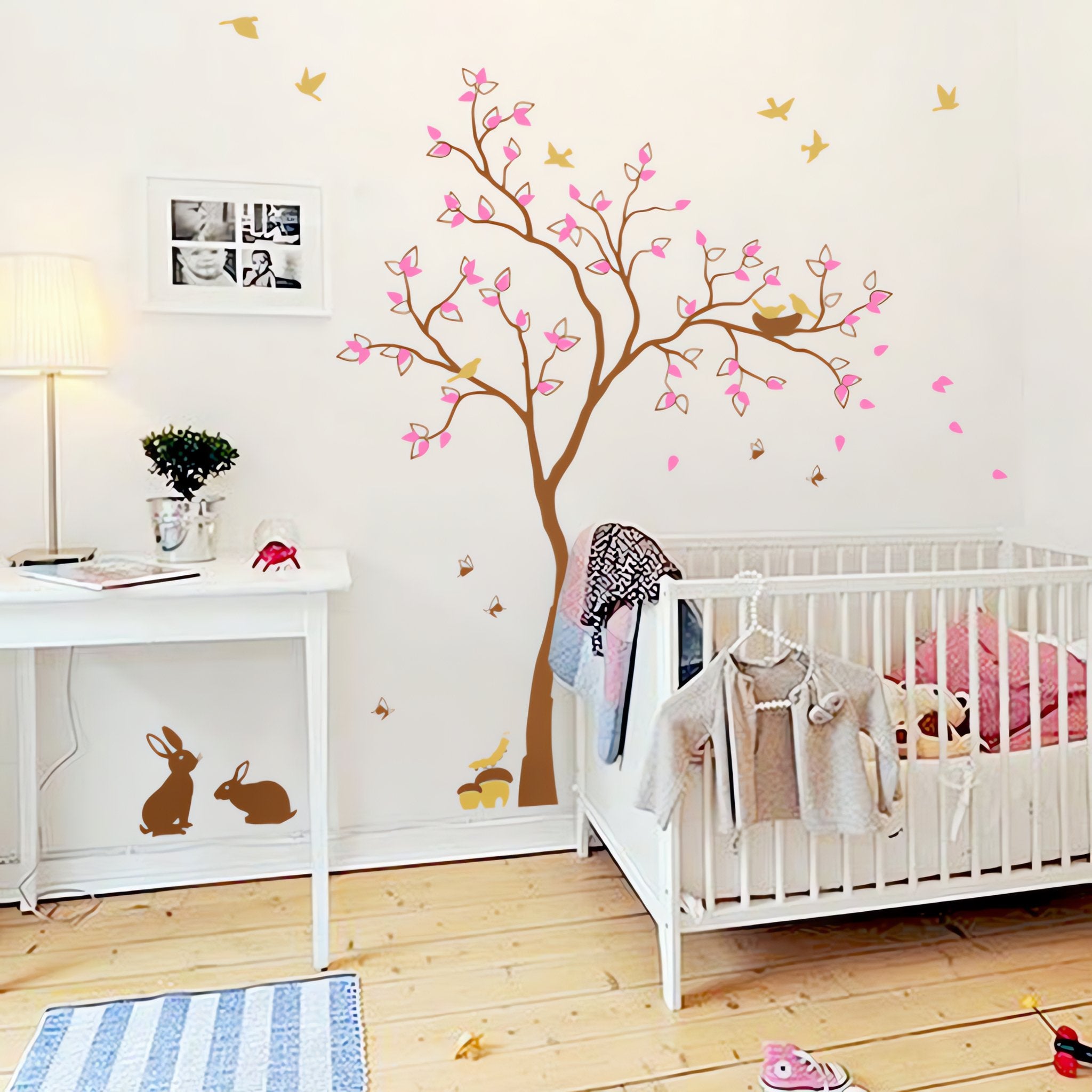 Tree wall sticker with birds, rabbits and a catterpillar in nursery with a crib and table.
