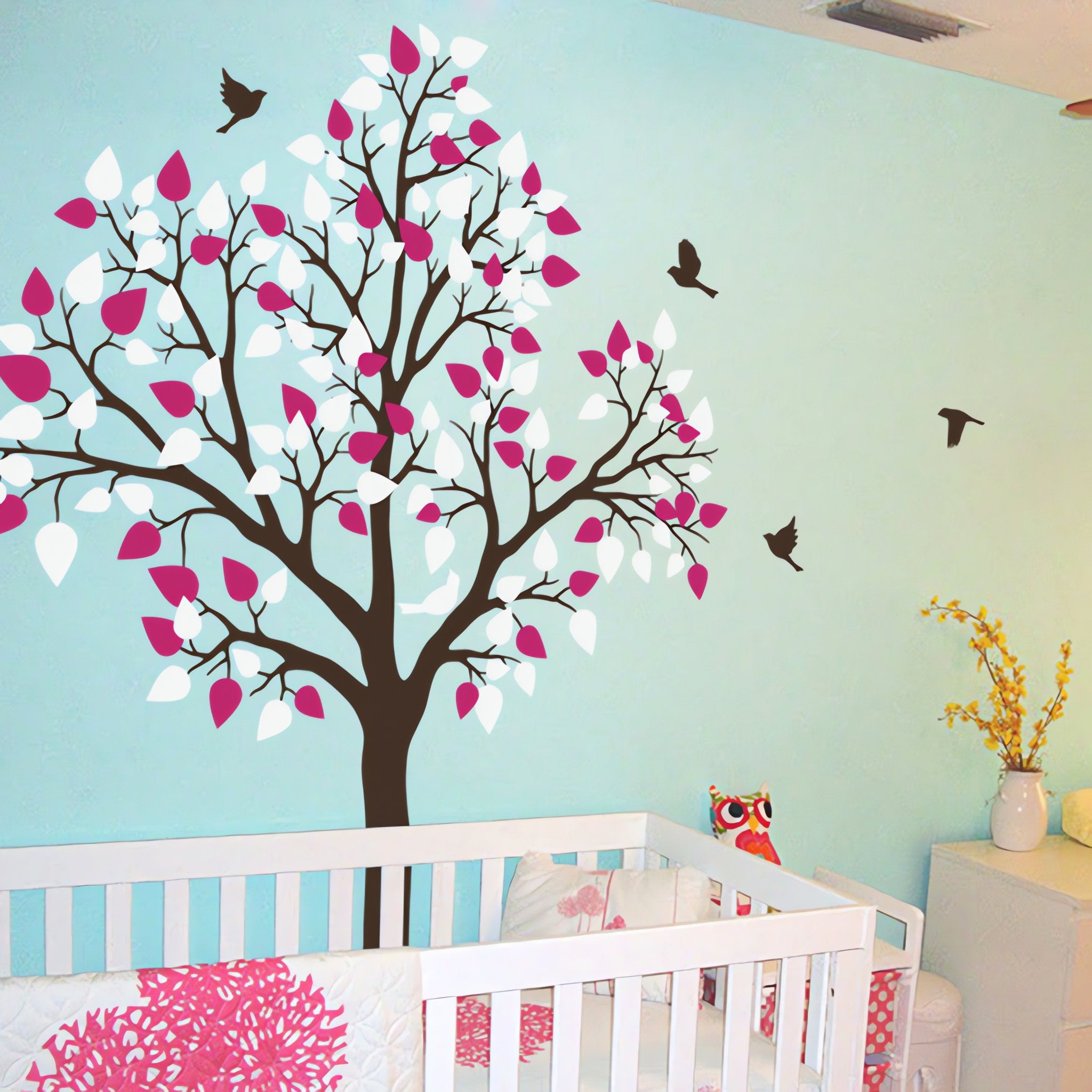 Tree wall sticker with birds in a nursery with a crib and a plant.