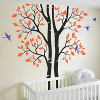 Tree wall sticker, split tree trunk with birds in a nursery near a crib.