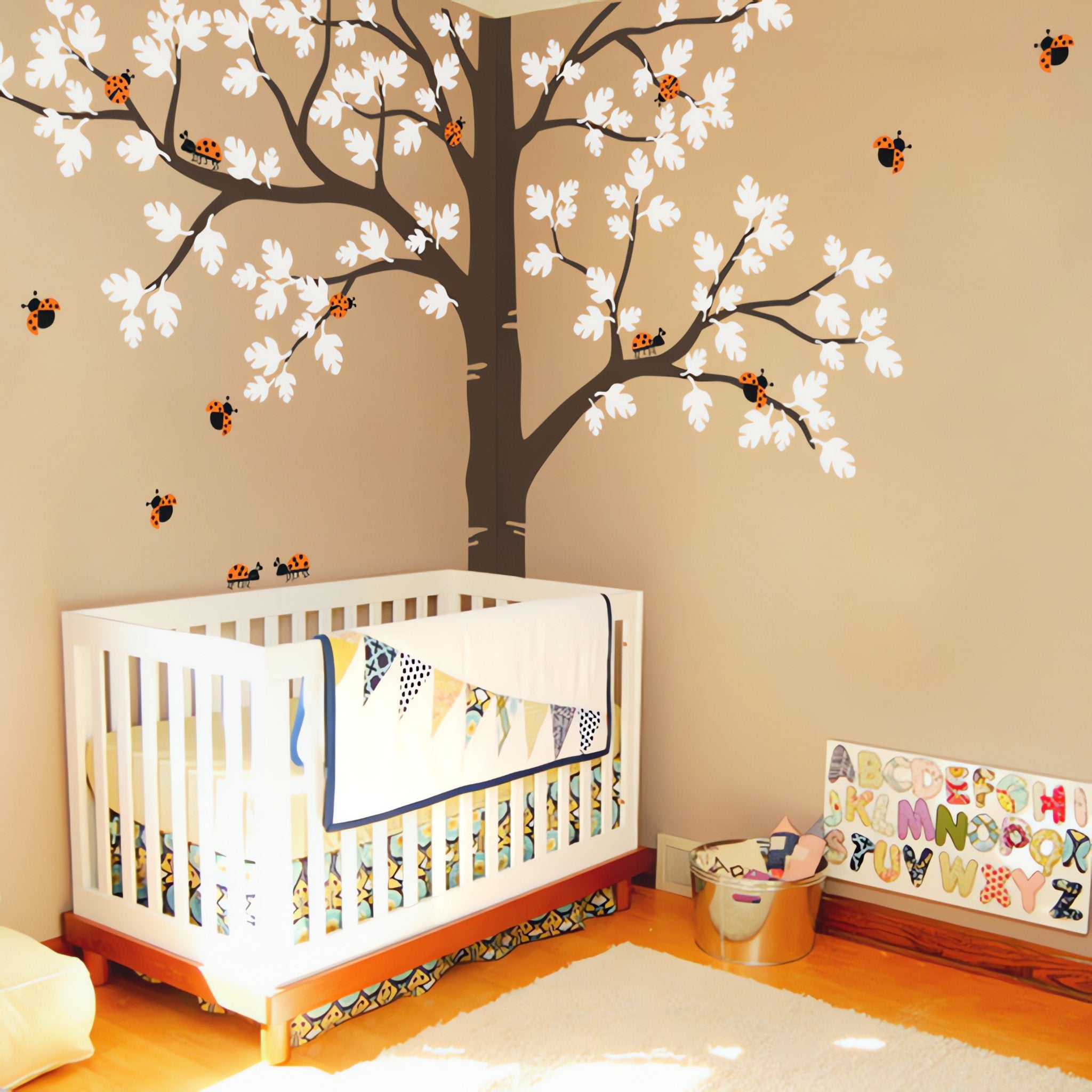 Corner tree wall sticker with a split trunk and ladybirds in a nursery with a crib and toys.