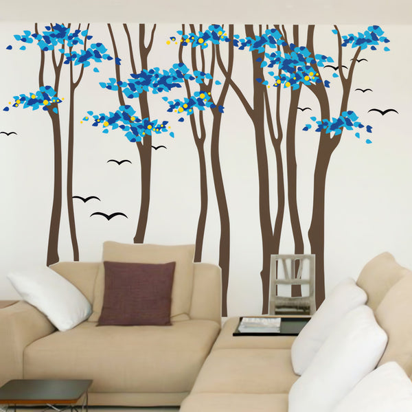 Tree wall sticker with stylish tall trees and birds in a living room with a corner couch.