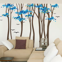 Tree wall sticker with stylish tall trees and birds in a living room with a corner couch.