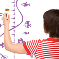 A mother charting the height of their child on a height chart with a mother charting the height of their child.
