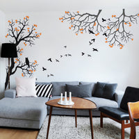 Tree wall sticker with birds, an owl and 2 hanging branches on the right in a living area with a sofa, a coffee table and chairs.