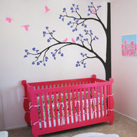 Tree wall sticker with branches on the left and birds in a nursery with a crib.